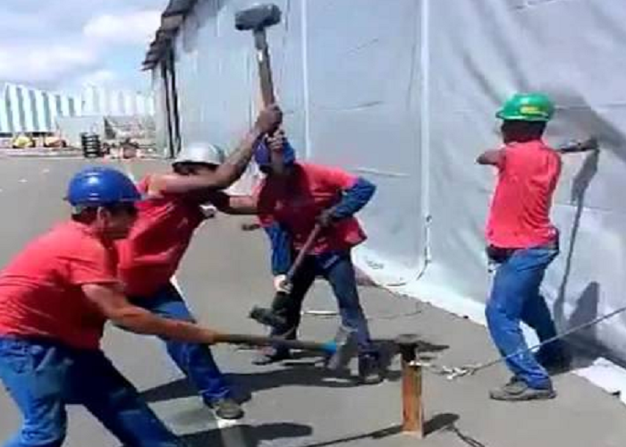 A Group Of Workers Hammer A Tent Peg In Perfect Harmony